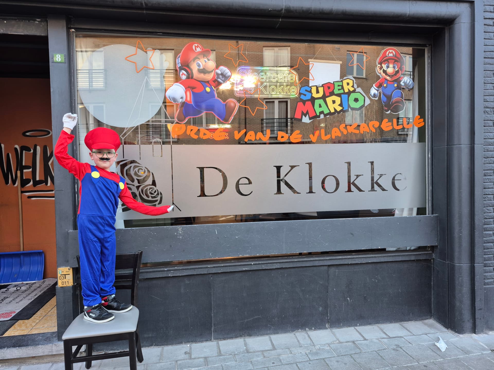 Jonge prins in Mario-verkleedkostuum voor het raam van De Klokke