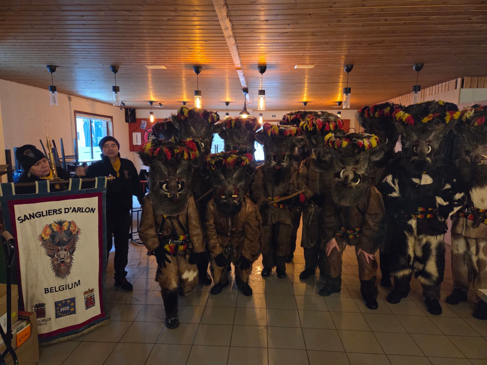 Carnavalsgroep Sangliers d'Arlon in everzwijnkostuums met hun vaandel