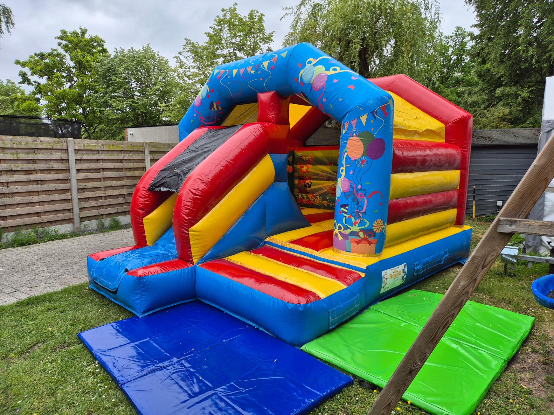 Springkasteel met glijbaan en valmatten op het gras