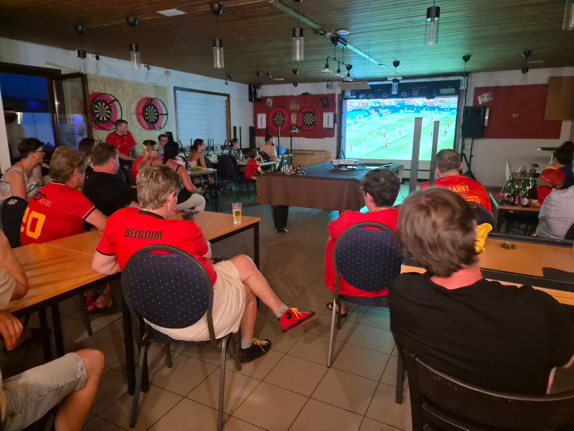 Supporters in rode truitjes kijken samen naar de match op het grote scherm