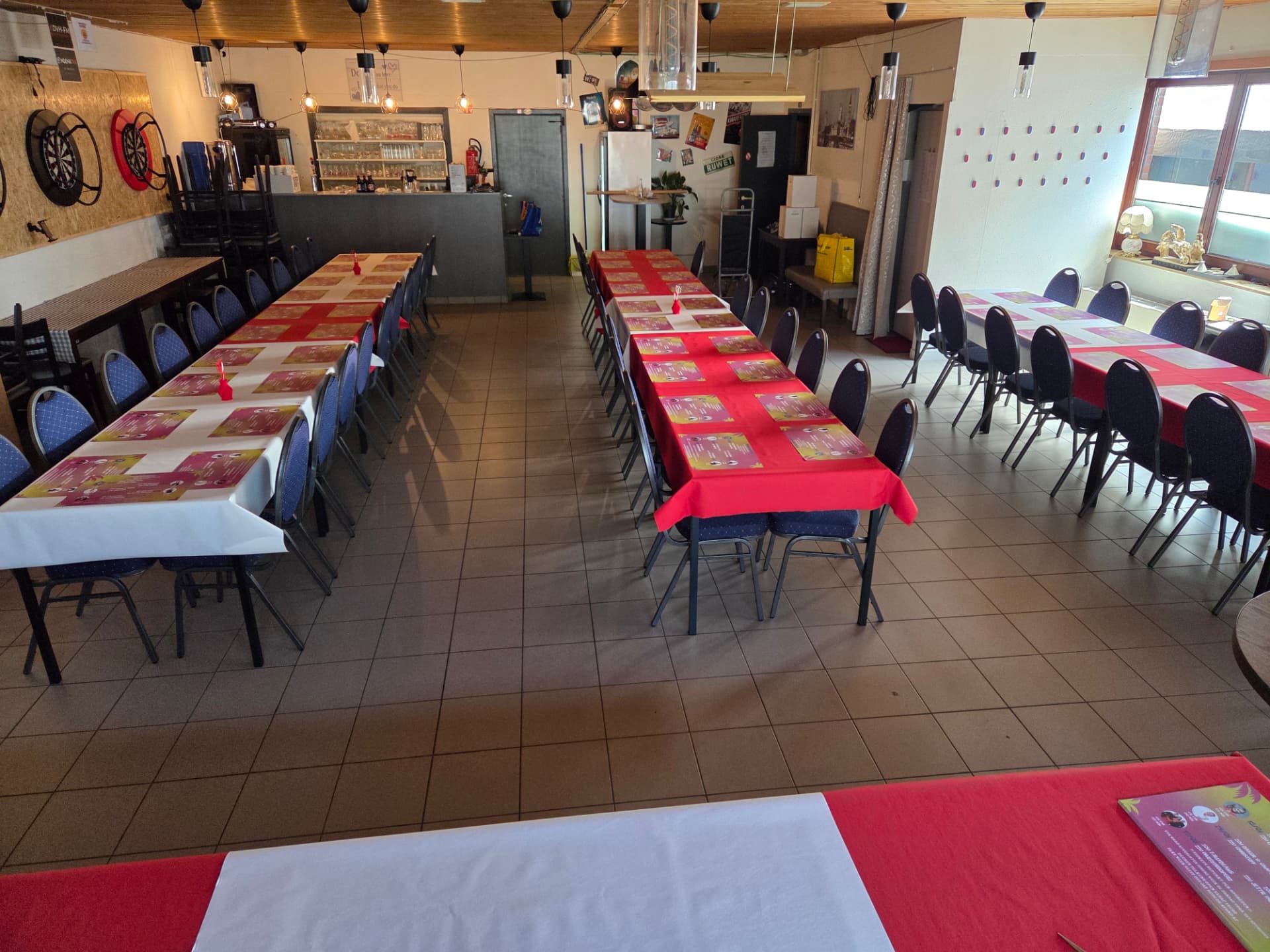 Feestzaal 't Rozenhof met toog, dartborden en tafels klaargezet voor een feest