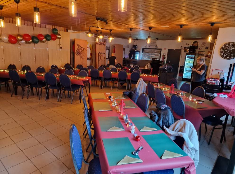 Overzicht van de volle zaal met rode tafels en ballonnen