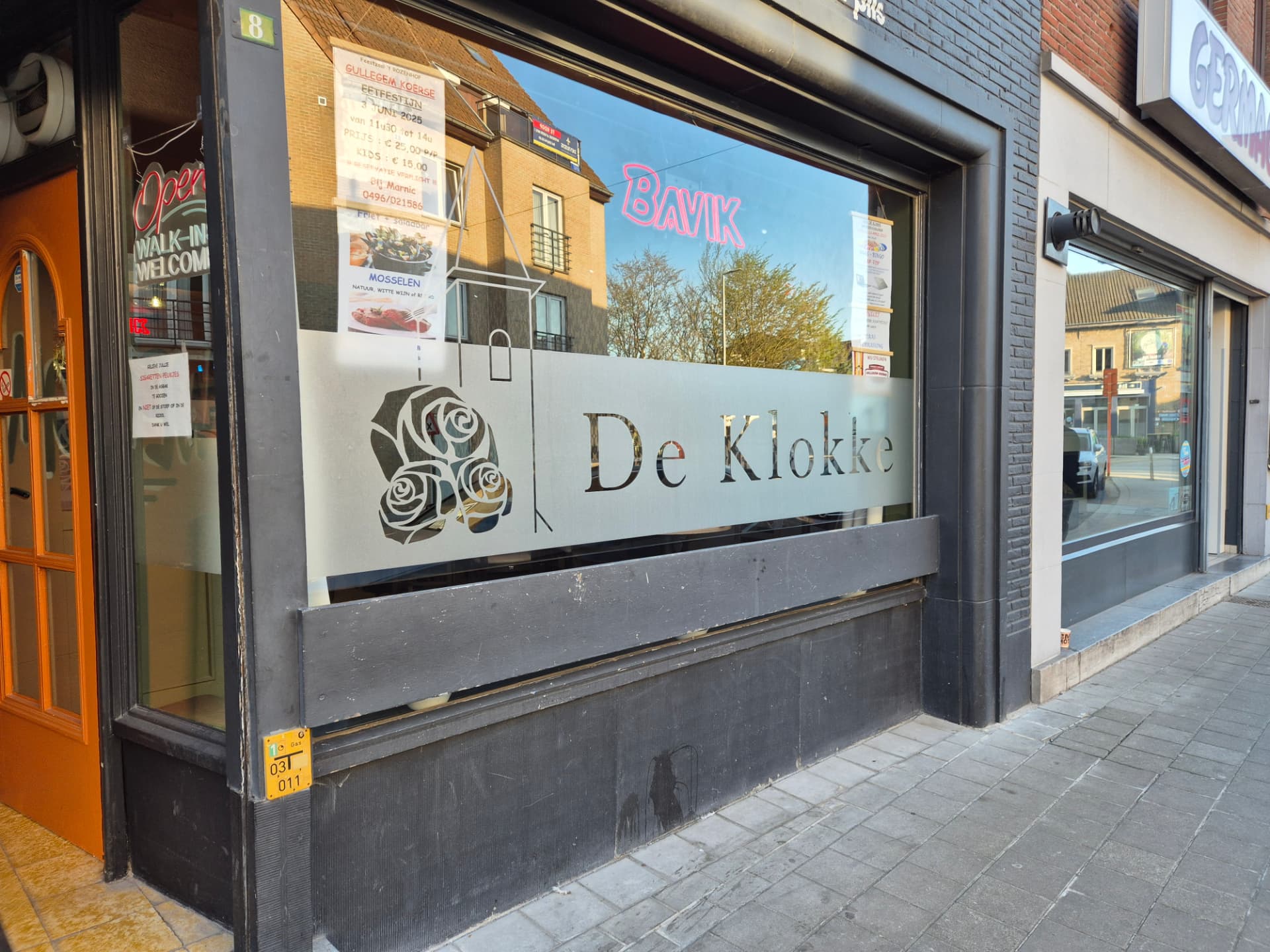 Het raam van De Klokke met logo en rozen aan Dorpsplein 8