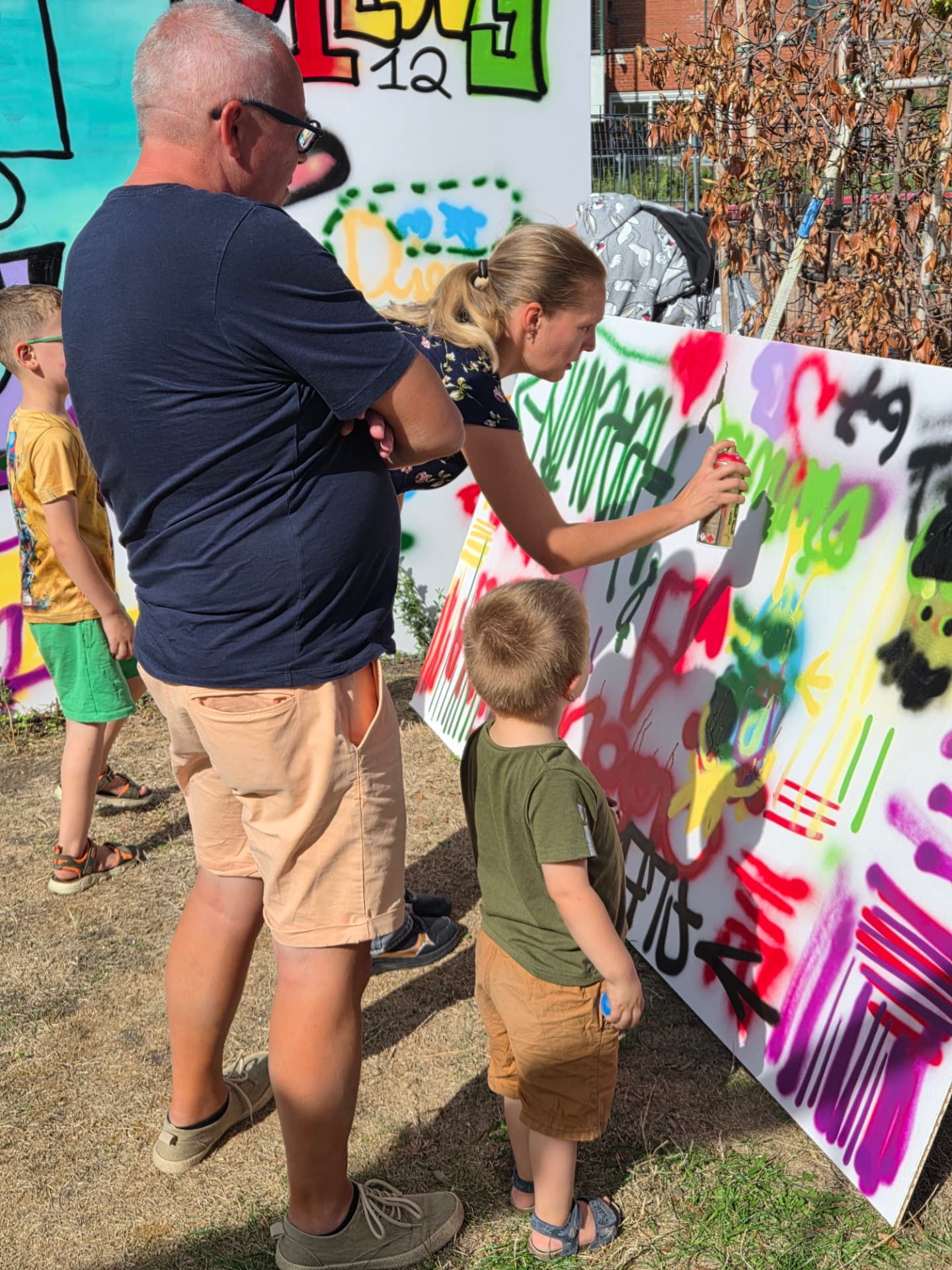 Kinderen en volwassenen maken samen kleurrijke graffiti in de tuin
