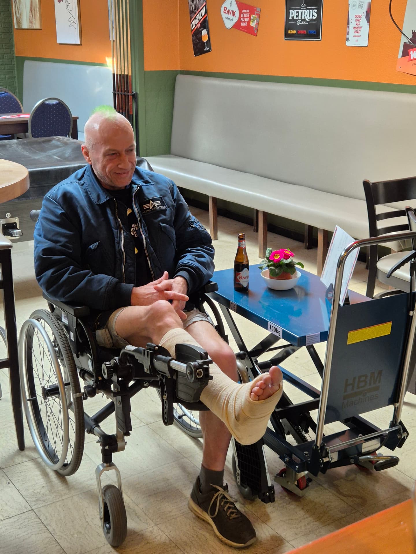 Vaste gast met het been in het verband geniet van een drankje in het café
