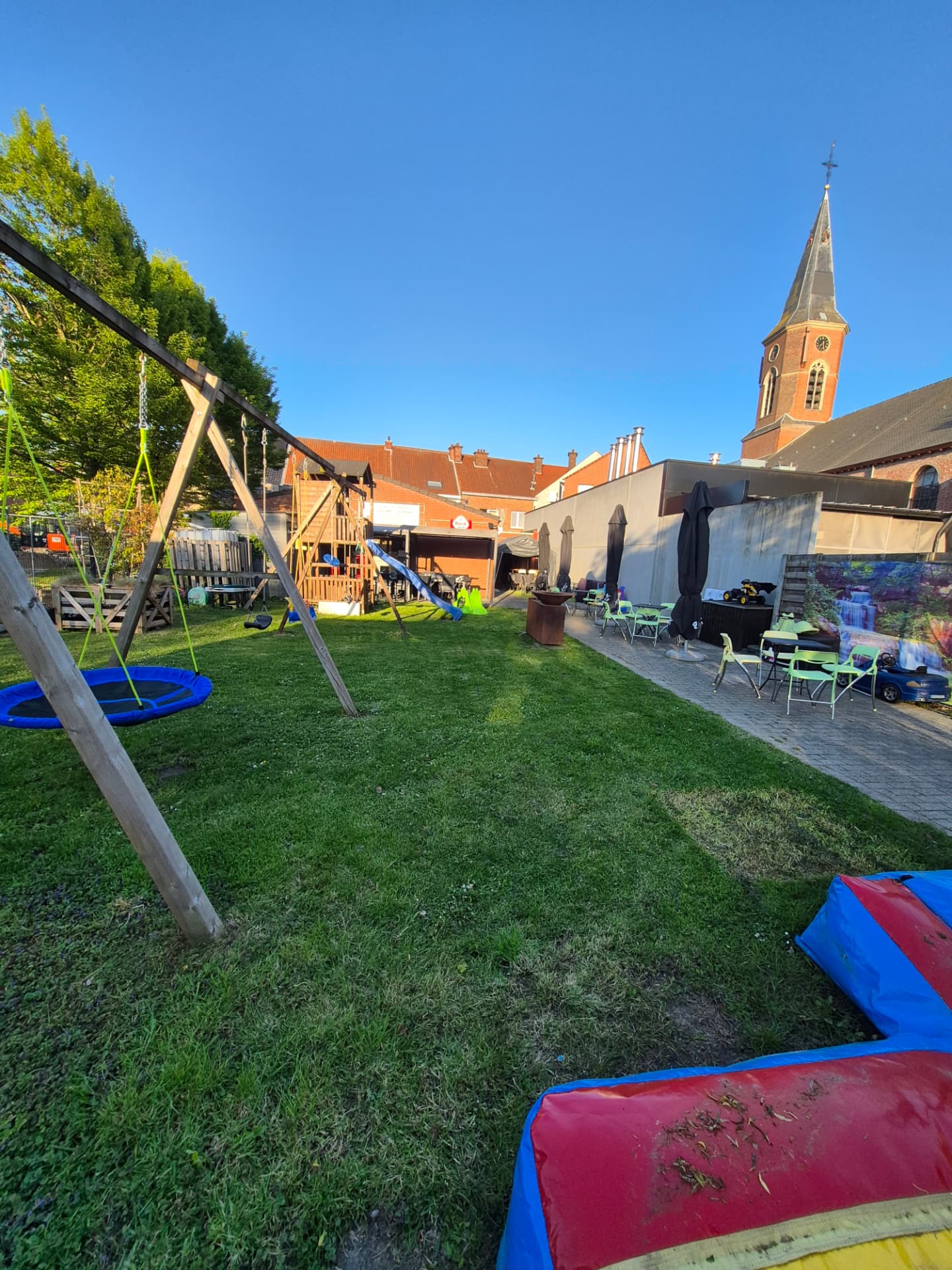 Overzicht van de tuin met schommels, speeltuin en terras