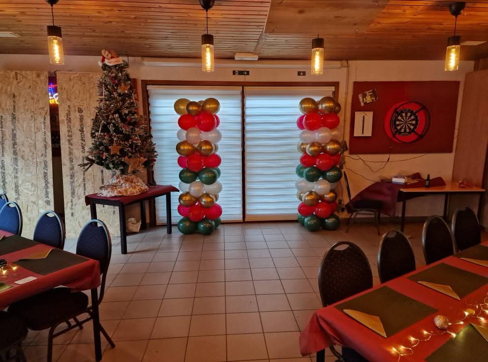 De zaal versierd met een kerstboom, ballonnenpilonnen en gedekte tafels